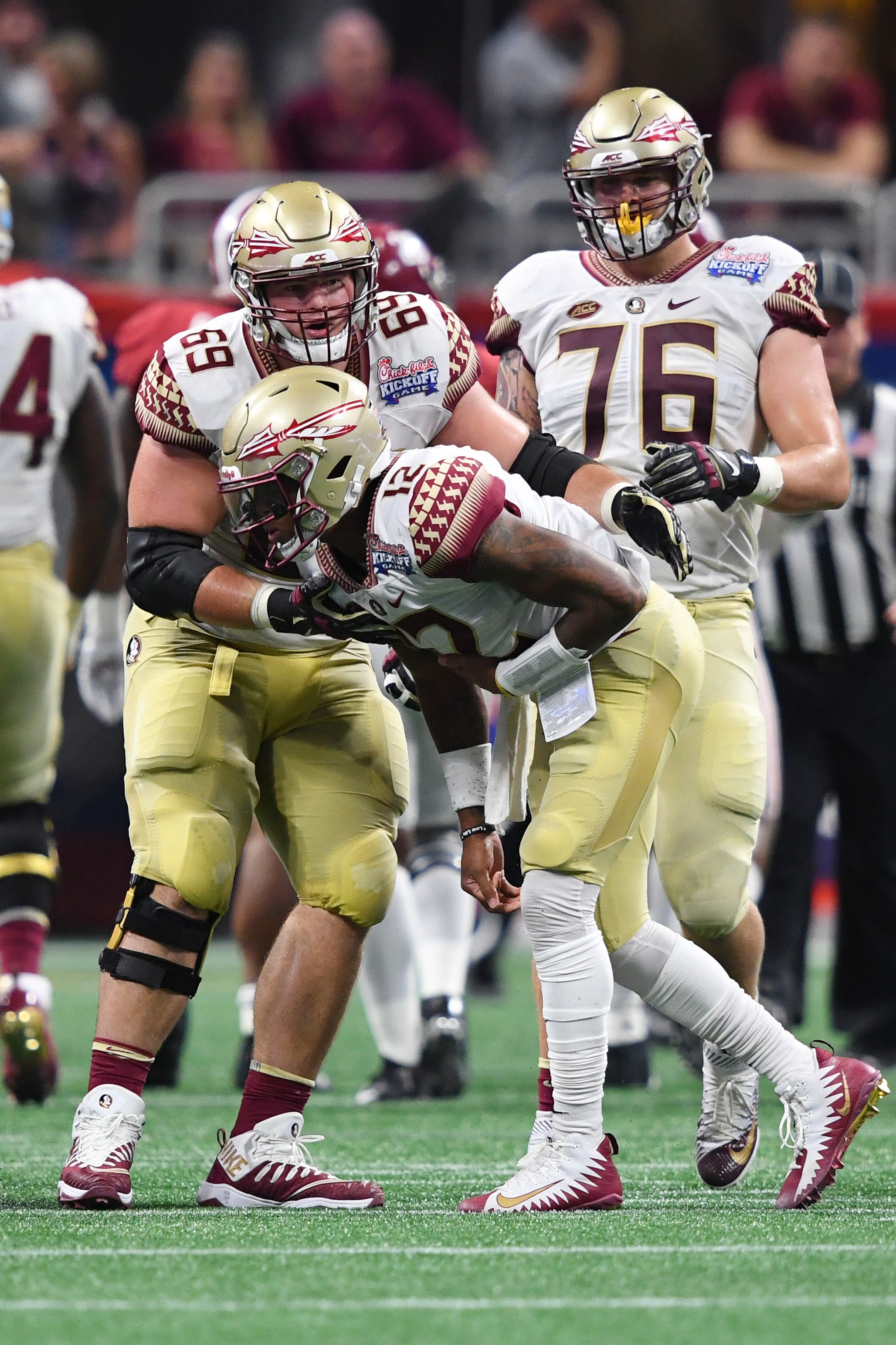 Sep 2, 2017; Atlanta, GA, USA; Florida State Seminoles quarterback Deondre Francois (12) is helped up by offensive lineman Landon Dickerson (69) and Florida State Seminoles offensive lineman Rick Leonard (76) after taking a hard hit against the Alabama Crimson Tide in the first quarter at Mercedes-Benz Stadium. Mandatory Credit: John David Mercer-USA TODAY Sports